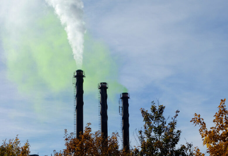 photo of factory with green smoke from chimneys to show greenwashing