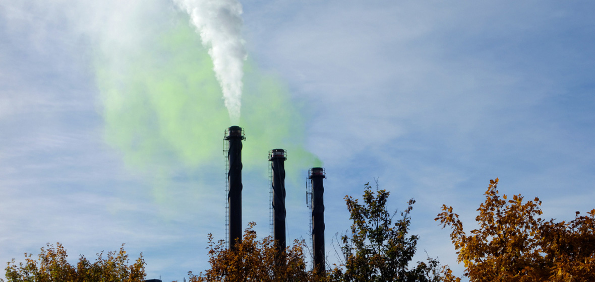 photo of factory with green smoke from chimneys to show greenwashing