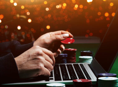 photo of hands playing poker on a card table in front of a computer to show online gambling