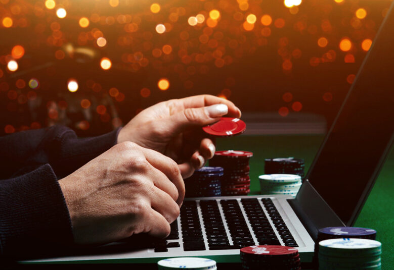 photo of hands playing poker on a card table in front of a computer to show online gambling