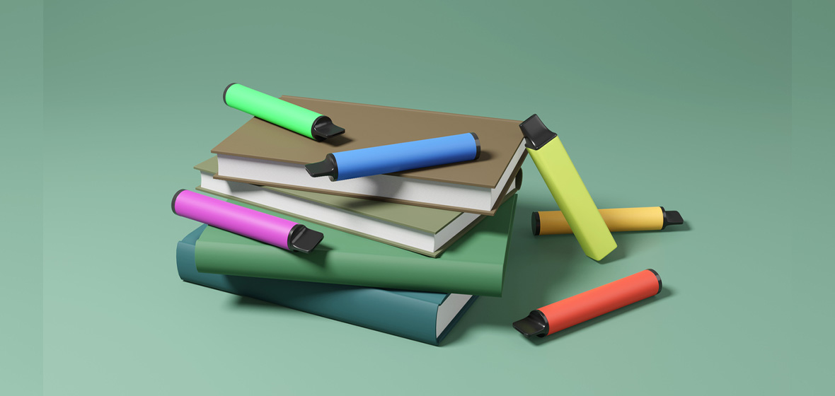 photo of books with colourful vapes lying on them resembling pens
